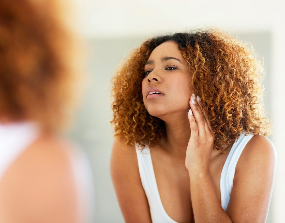 Brush On Block image of woman looking critically at skin in mirror