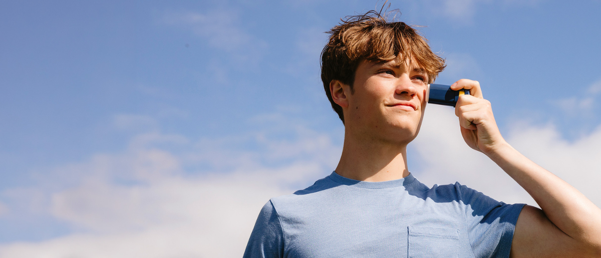 Young athlete applying Brush On Block Quick Stick mineral sunscreen to his cheek