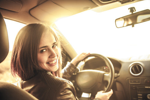 brush on block image of tanned woman driving in car smiling