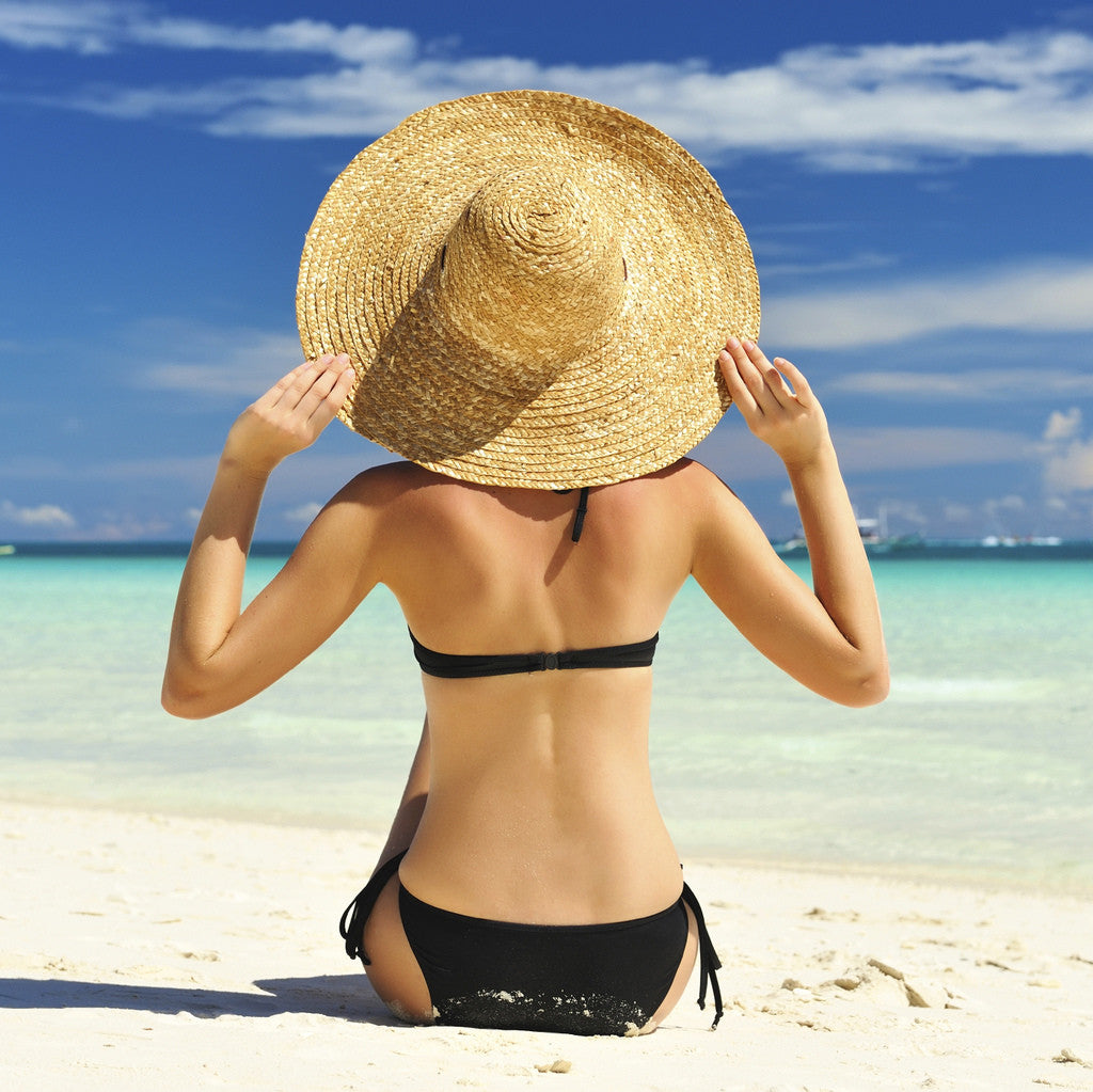 brush on block image of woman on beach in bathing suit and big hat