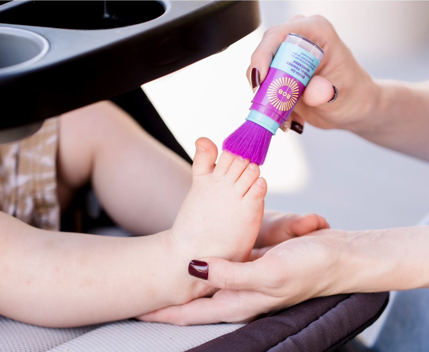 Parent applying BOB KIDS Mineral Powder Sunscreen to child's toes