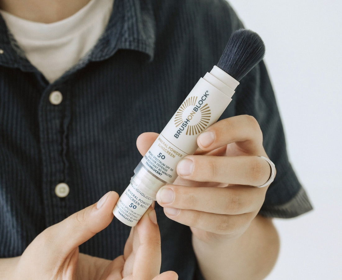 Person inserting a Brush On Block SPF 50 mineral powder refill into the Brush On Block SPF 50 brush.