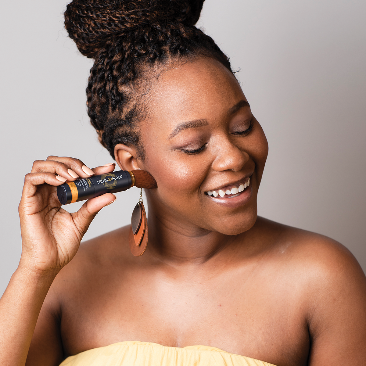 Woman applying BRUSH ON BLOCK® mineral powder sunscreen in translucent