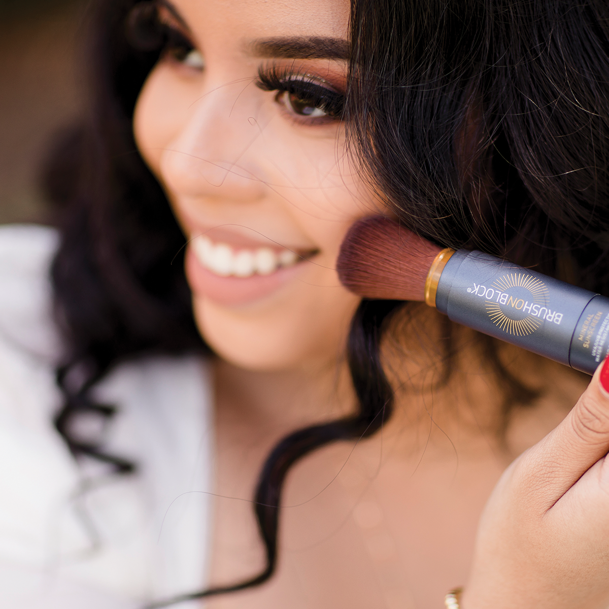Woman applying BRUSH ON BLOCK® Tinted Mineral Sunscreen