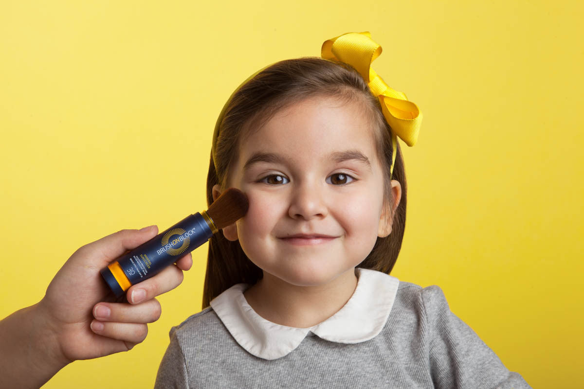 small child with kid-friendly brush on block mineral sunscreen