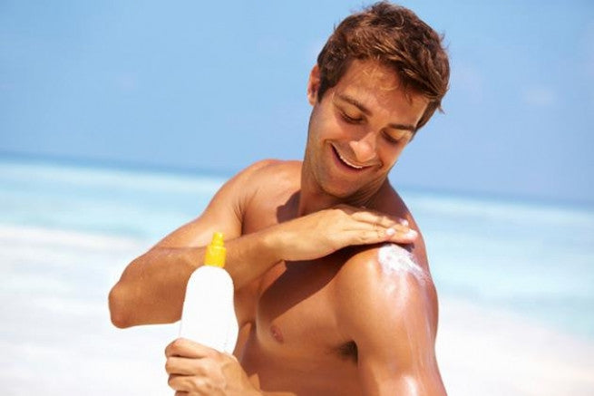 Brush On Block image of man applying sunscreen to shoulders at the beach