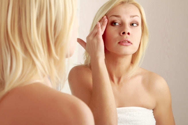 Brush On Block image of woman looking at face in mirror