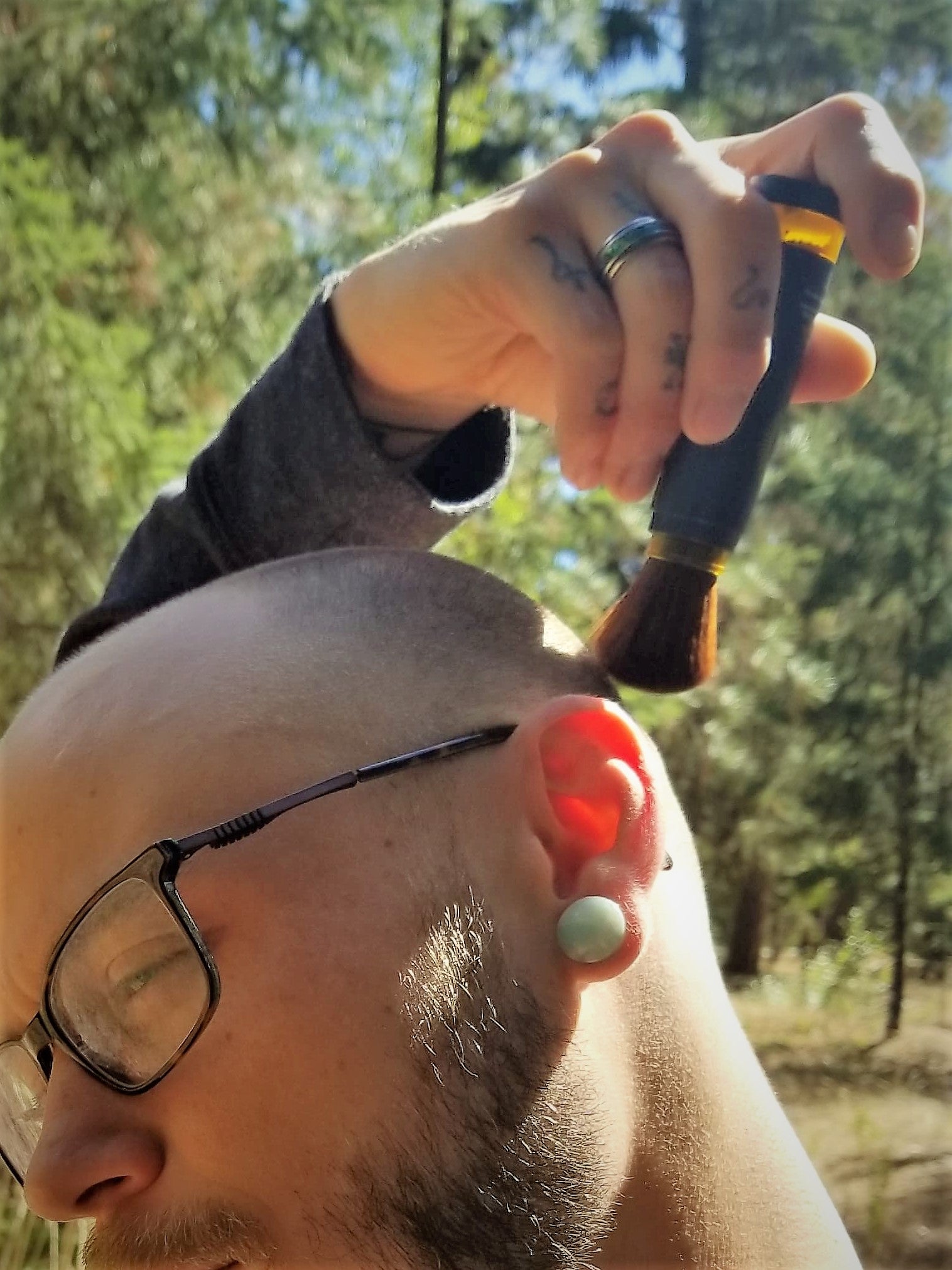 Man applying Brush On Bloc to bald head, ears.