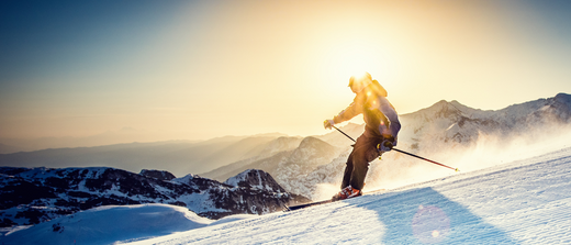 A skier on a bright mountain slope with strong sun glare and reflective snow, highlighting high-altitude winter UV.