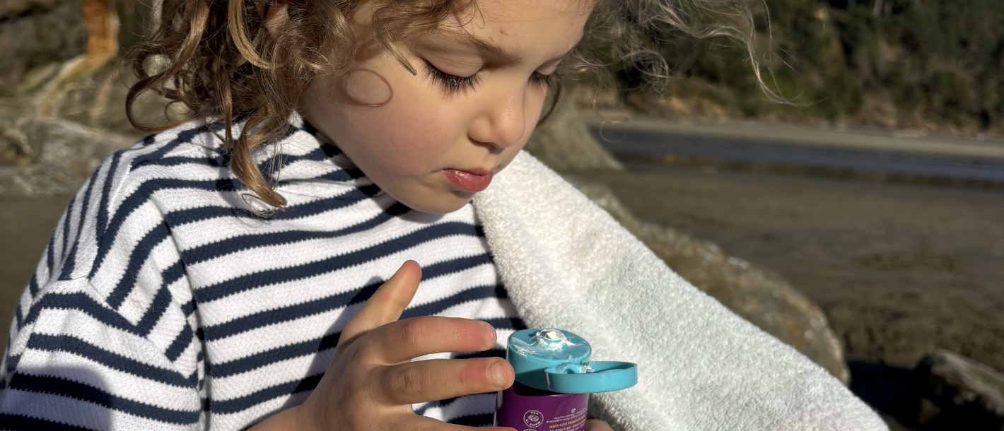 Young girl applying BOB KIDS mineral sunscreen lotion to her face, illustrating how to choose and use mineral sunscreen for kids