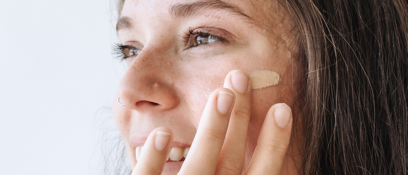 Woman with sensitive skin applying Brush On Block Sheer Genius mineral sunscreen SPF 50 to her face