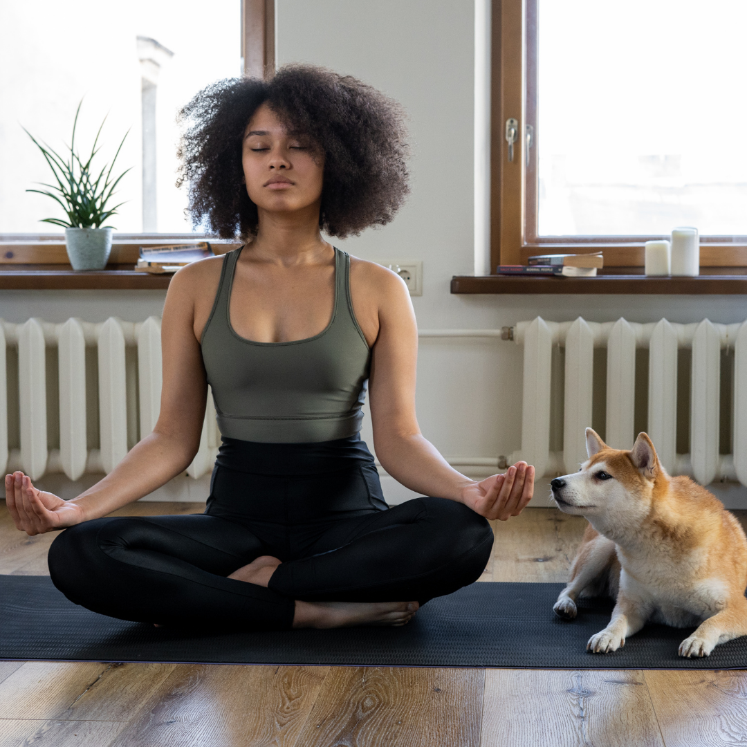 Woman doing yoga with dog next to her