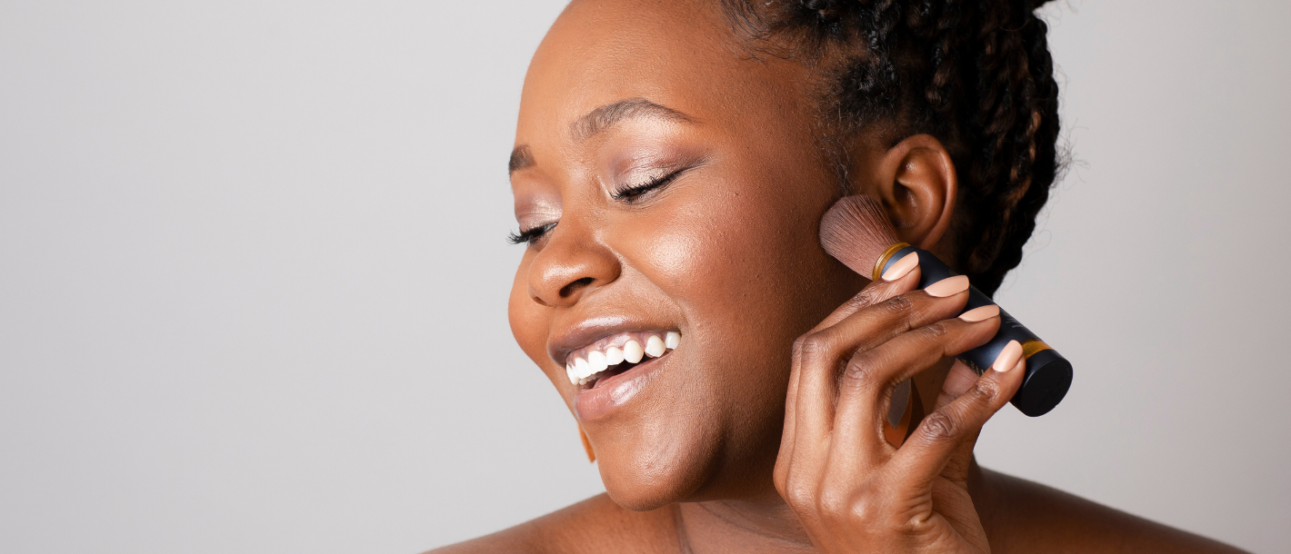 Woman with deep skin tone applying Brush On Block translucent mineral powder sunscreen with no white cast