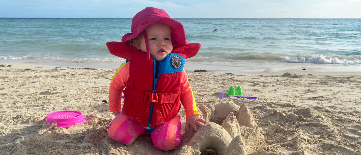 Child on the beach with sun protective clothing and hat. 