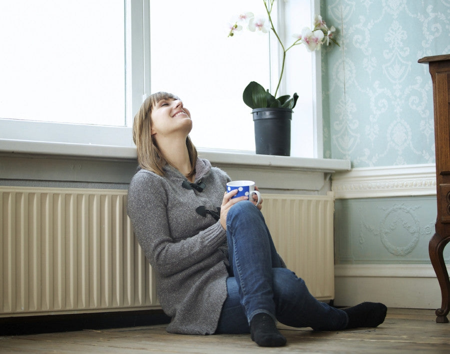 Brush On Block image of woman in sweater leaning on radiator