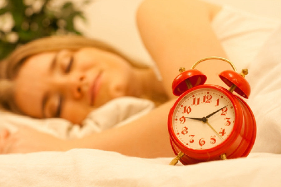 Brush On Block image of woman sleeping with alarm clock in foreground.