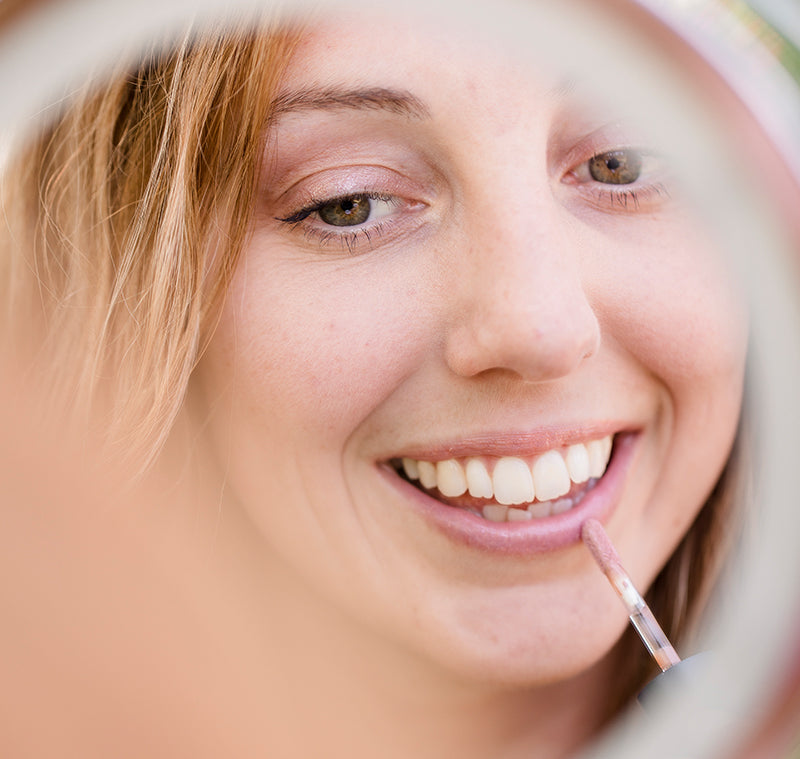 BRUSH ON BLOCK® image of woman applying Protective Lip Oil SPF 32