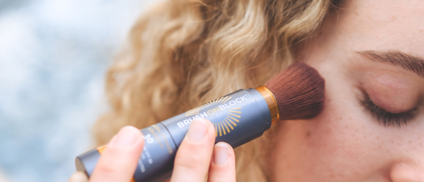 Close-up applying Brush On Block mineral powder sunscreen to cheek, gentle, irritation-free SPF for sensitive skin.
