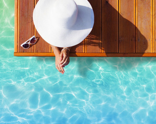 Brush On Block image of person laying poolside with large hat