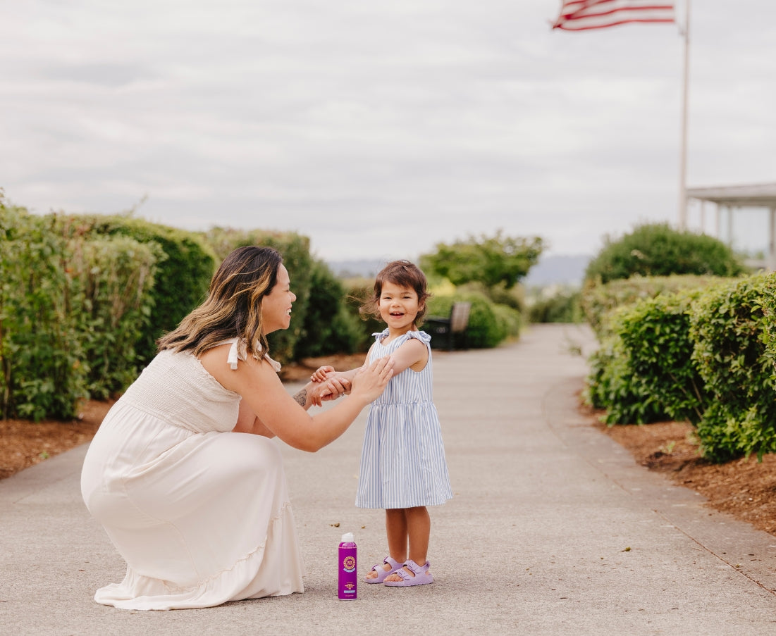 Woman and child on a path outside applying Brush On Block mineral spray on lotion