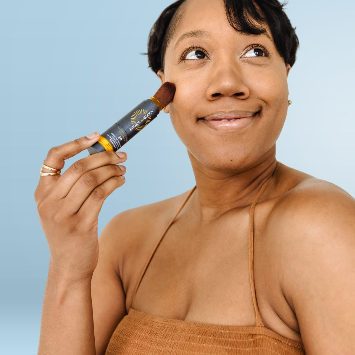 Woman applying Brush On Block SPF 30 Translucent Mineral Sunscreen