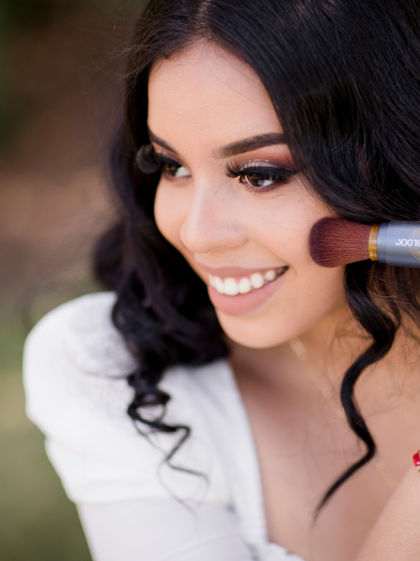 Close-up photo of a woman applying Brush On Block SPF 30 mineral powder sunscreen to her cheek