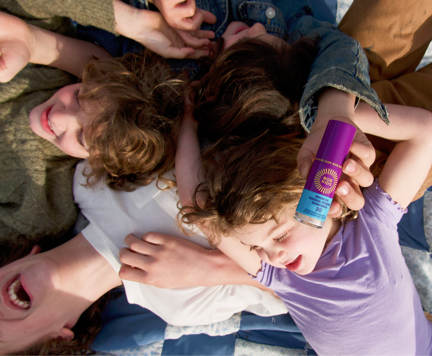 Children playing together holding up BOB KIDS Brush On Mineral Sunscreen