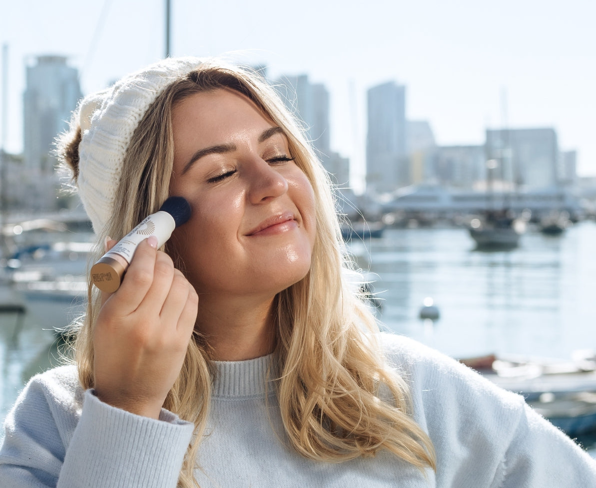 Woman applying Brush On Block mineral powder sunscreen on cloudy day