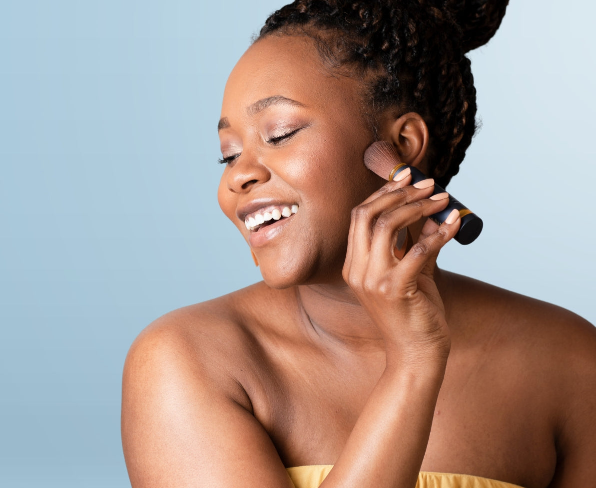 Woman applying makeup-friendly Brush On Block mineral powder sunscreen over makeup. 