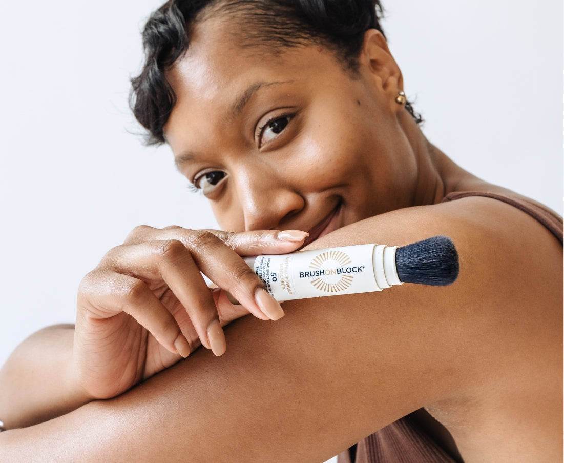 Woman holding Brush On Block SPF 50 brush with cap off